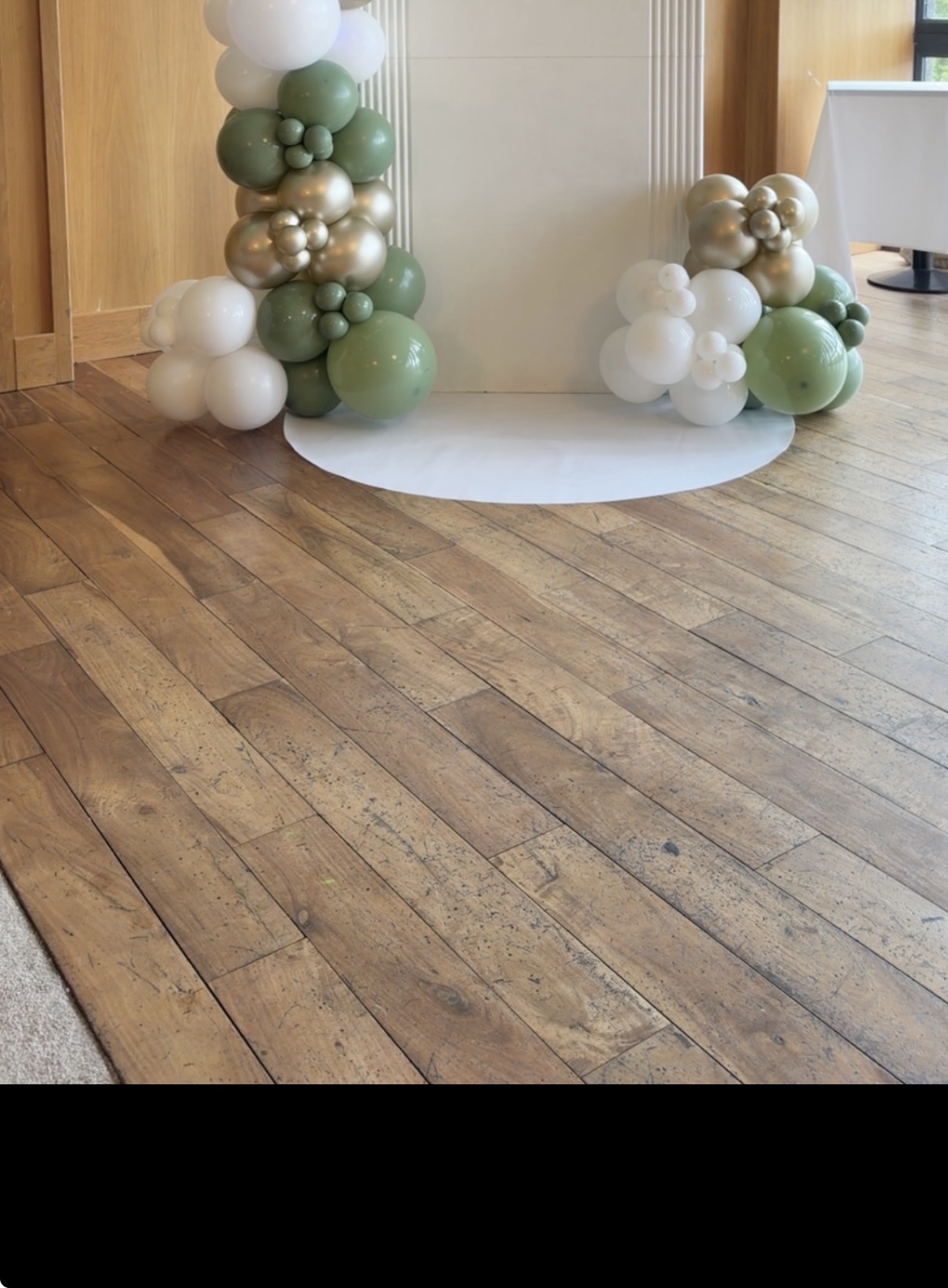 White semi-circle floor mat with sage and cream balloon garland
