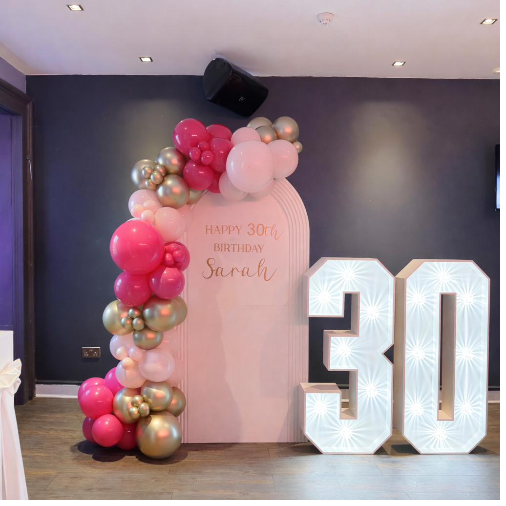 Pink and gold 30th birthday balloon arch with marquee numbers